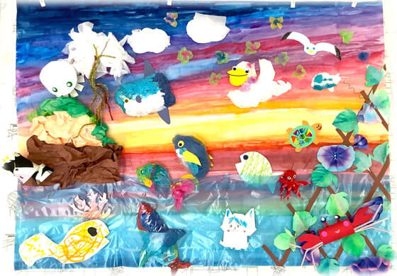 海を泳ぐお魚さんの絵が描かれた敷物に、子供たちが楽しそうに寝転んでいる画像